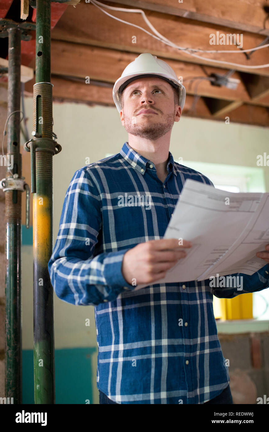 Architect Inside House Being Renovated Studying Plans Stock Photo
