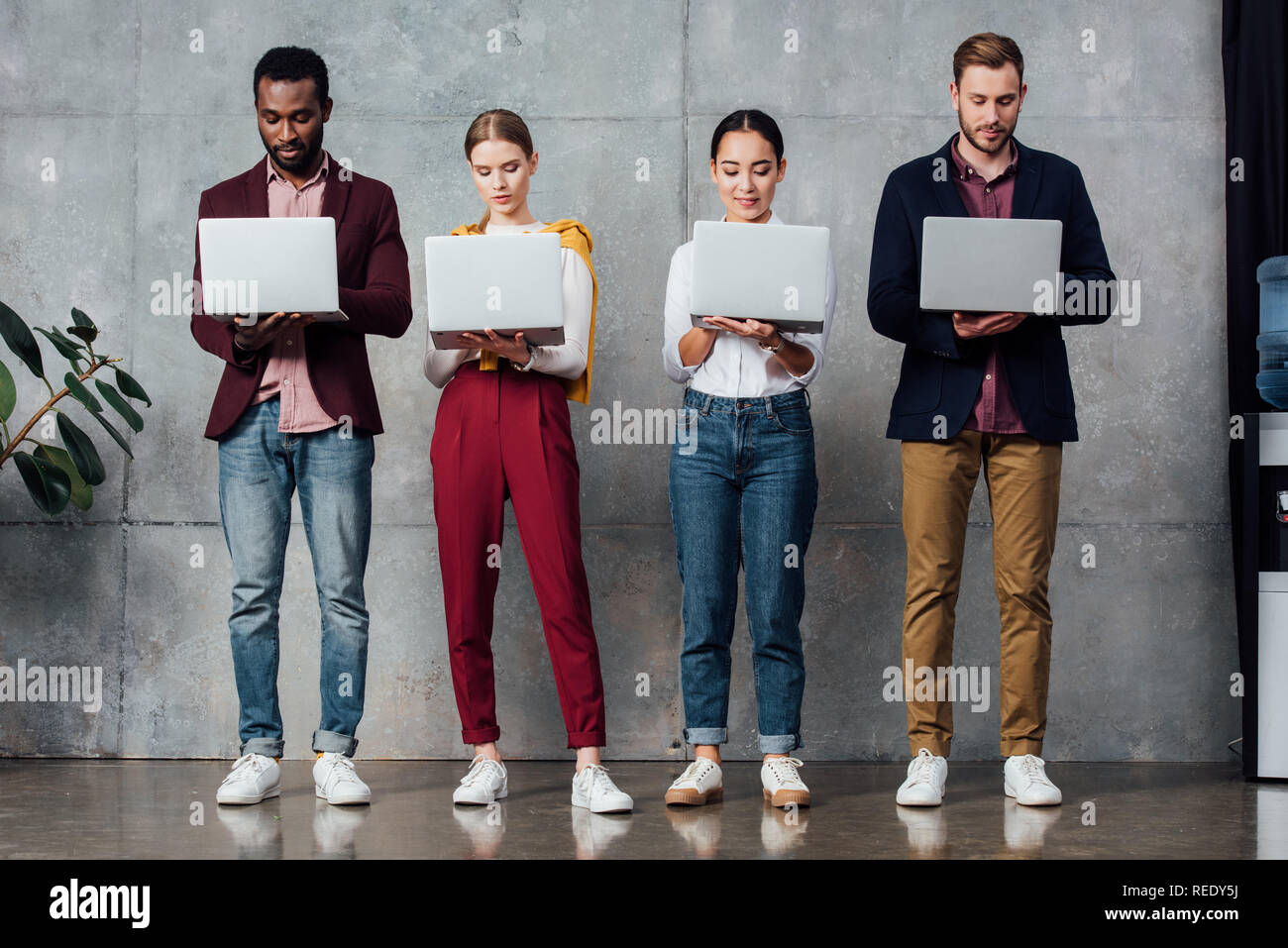 concentrated multiethnic casual businesspeople using laptops in waiting hall Stock Photo
