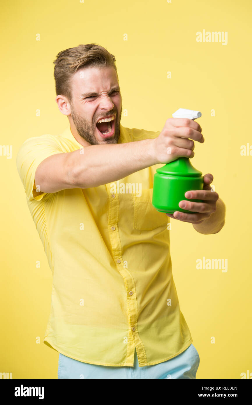 Macho hold plastic spray bottle as gun yellow background. Guy with