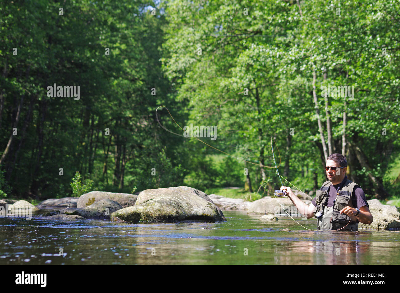 Fly fishermen in action. Catch of fish, fly fishing scene, freshwater fishing, trout fishing Stock Photo
