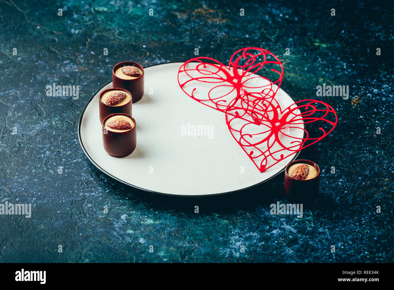 Valentine's day table setting. Table set with plate, hearts, red gift boxws, cjocolate sweets, knife and fork onblue background. Top view and copy spa Stock Photo