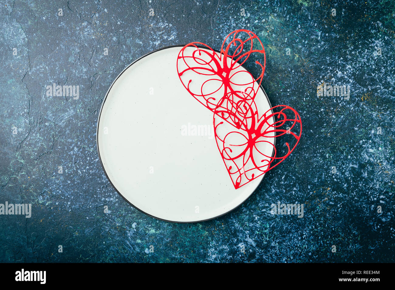 Valentine's day table setting. Table set with plate, hearts, red gift boxws, cjocolate sweets, knife and fork onblue background. Top view and copy spa Stock Photo