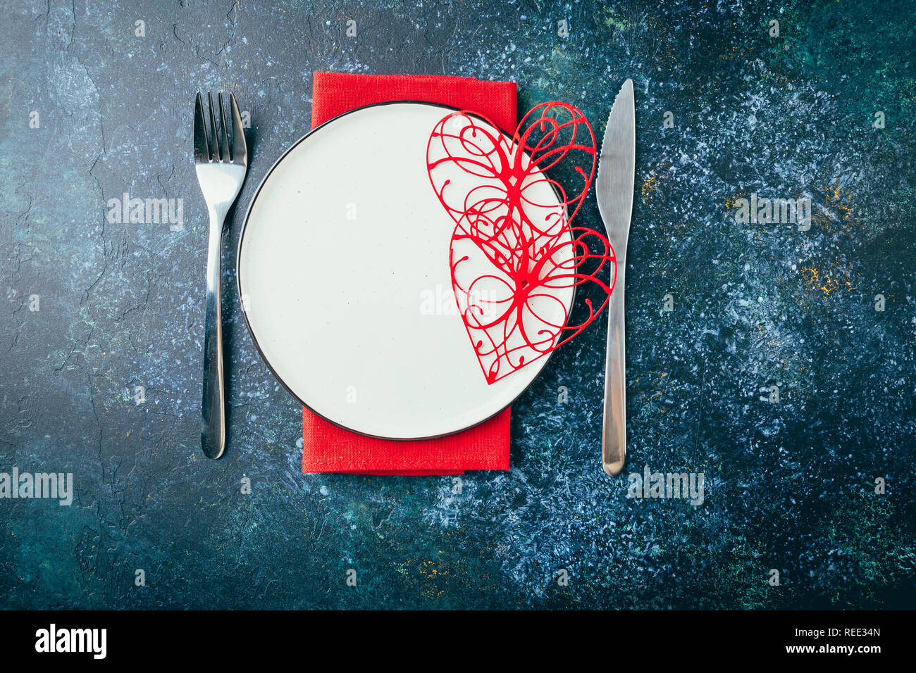 Valentine's day table setting. Table set with plate, hearts, red gift boxws, cjocolate sweets, knife and fork onblue background. Top view and copy spa Stock Photo