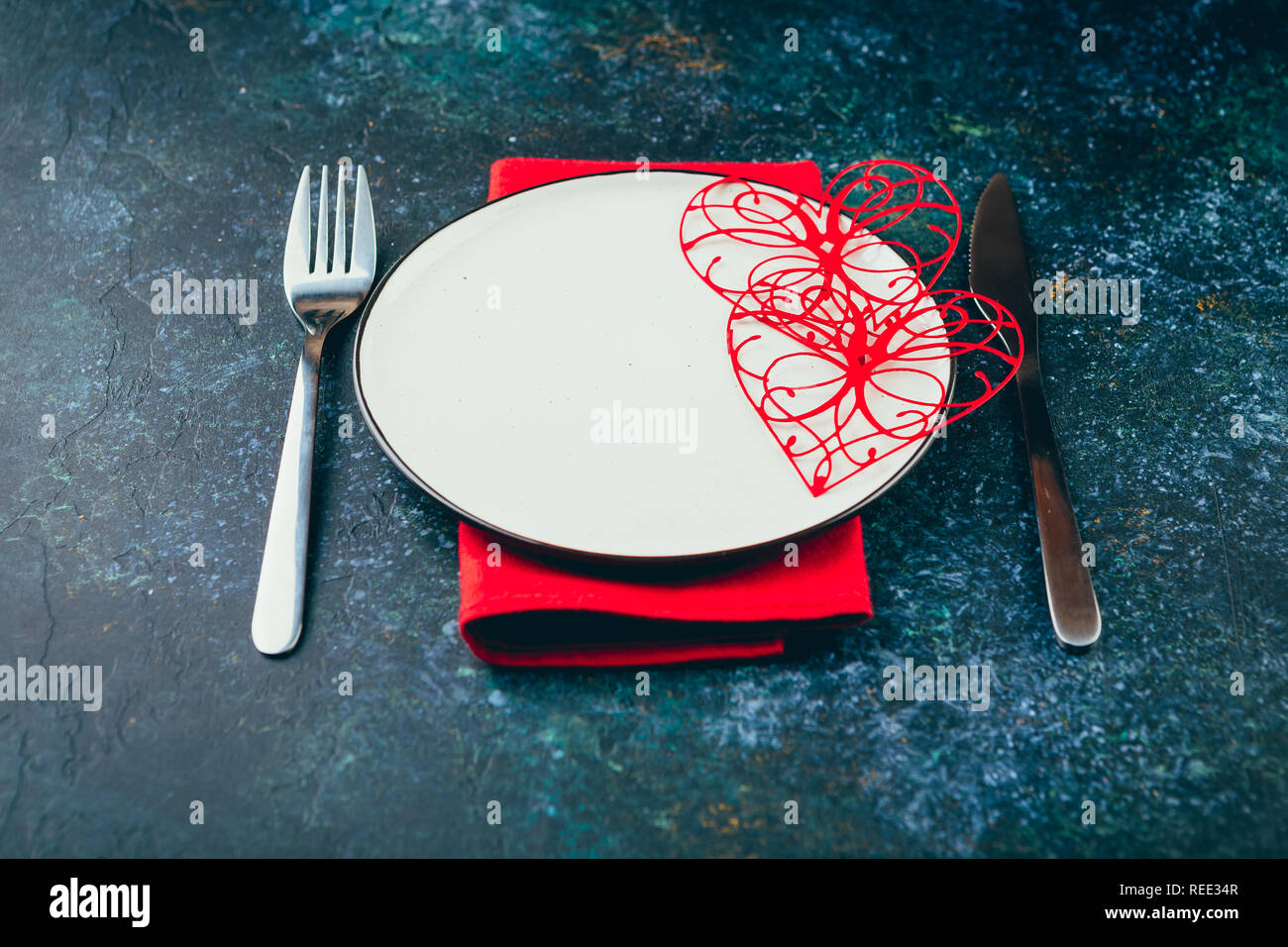 Valentine's day table setting. Table set with plate, hearts, red gift boxws, cjocolate sweets, knife and fork onblue background. Top view and copy spa Stock Photo