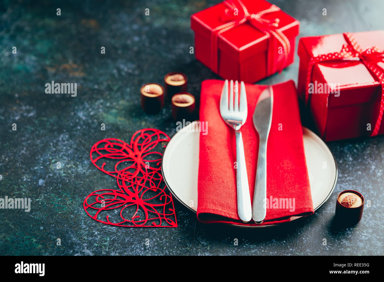 Valentine's day table setting. Table set with plate, hearts, red gift boxws, cjocolate sweets, knife and fork onblue background. Top view and copy spa Stock Photo