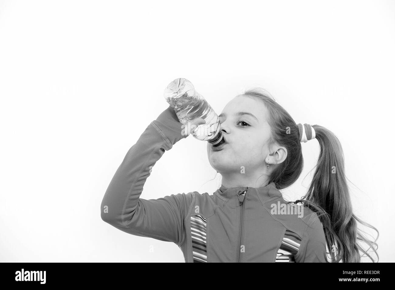 Fluid balance, hydration. Child feel thirsty in pink suit isolated on white. Health and healthy drinking. Girl drink water from bottle. Dehydration, thirst concept. Stock Photo