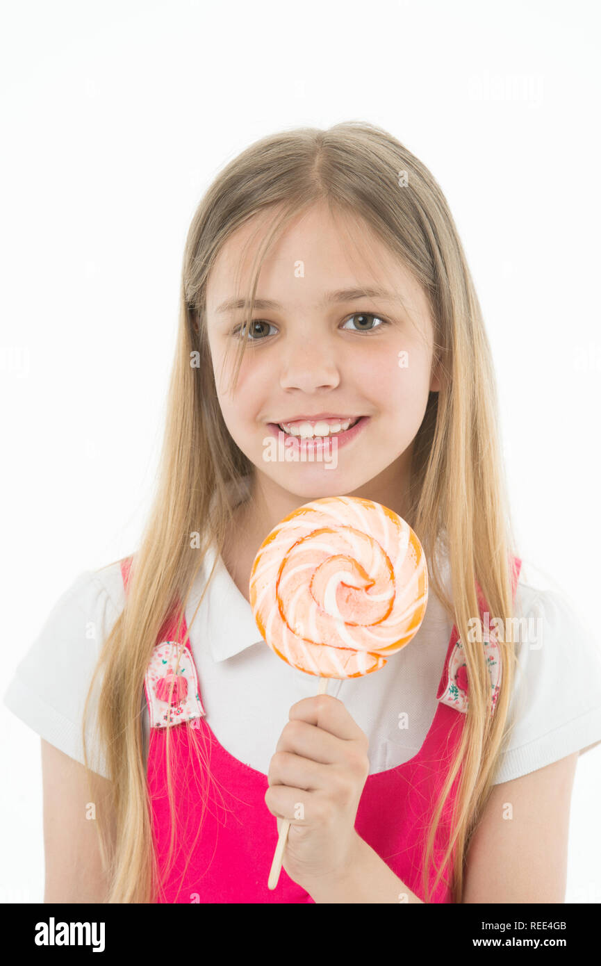 Girl smile with lollipop isolated on white. Small child smiling with candy on stick. Happy kid with swirl caramel. Food and dessert. Enjoying sweet lollipop. Diet and dieting. Stock Photo