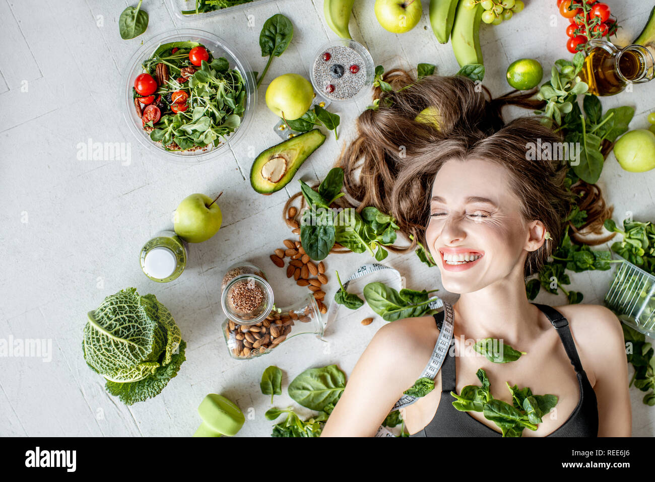 Beauty portrait of a woman surrounded by various healthy food lying on the floor. Healthy eating and sports lifestyle concept Stock Photo