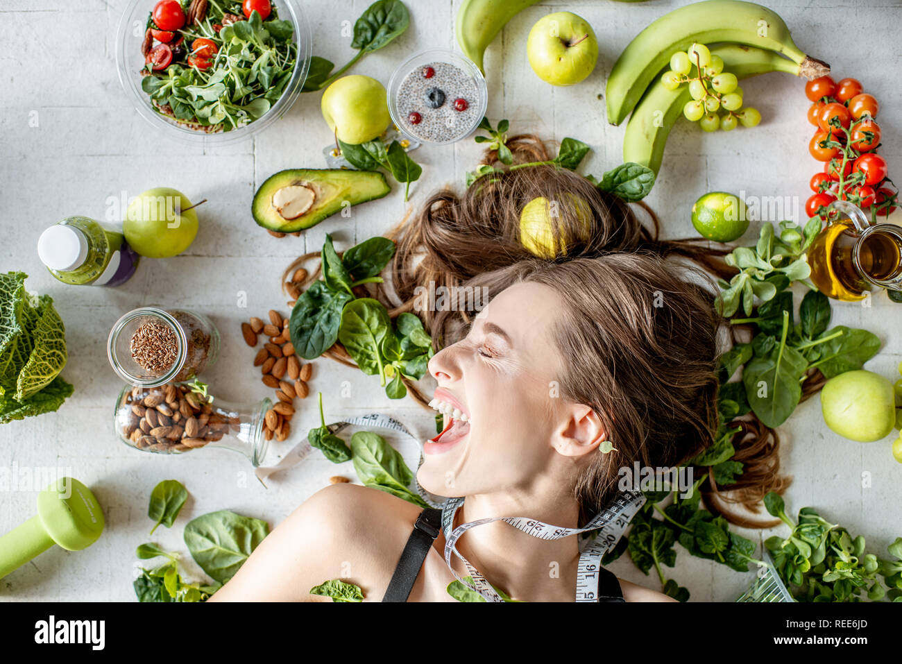 Beauty portrait of a woman surrounded by various healthy food lying on the floor. Healthy eating and sports lifestyle concept Stock Photo