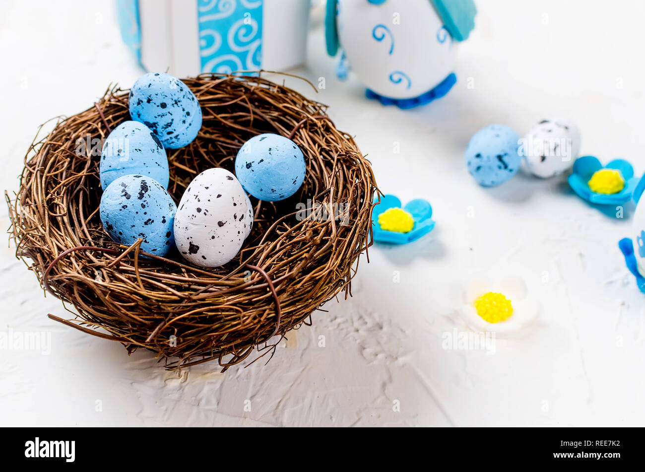 Easter decorative white and blue eggs in a nest and two toy chickens in ...