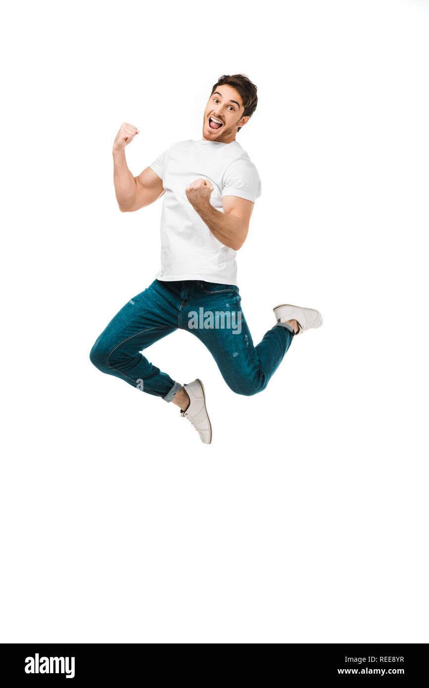 excited young man jumping and smiling at camera isolated on white Stock Photo