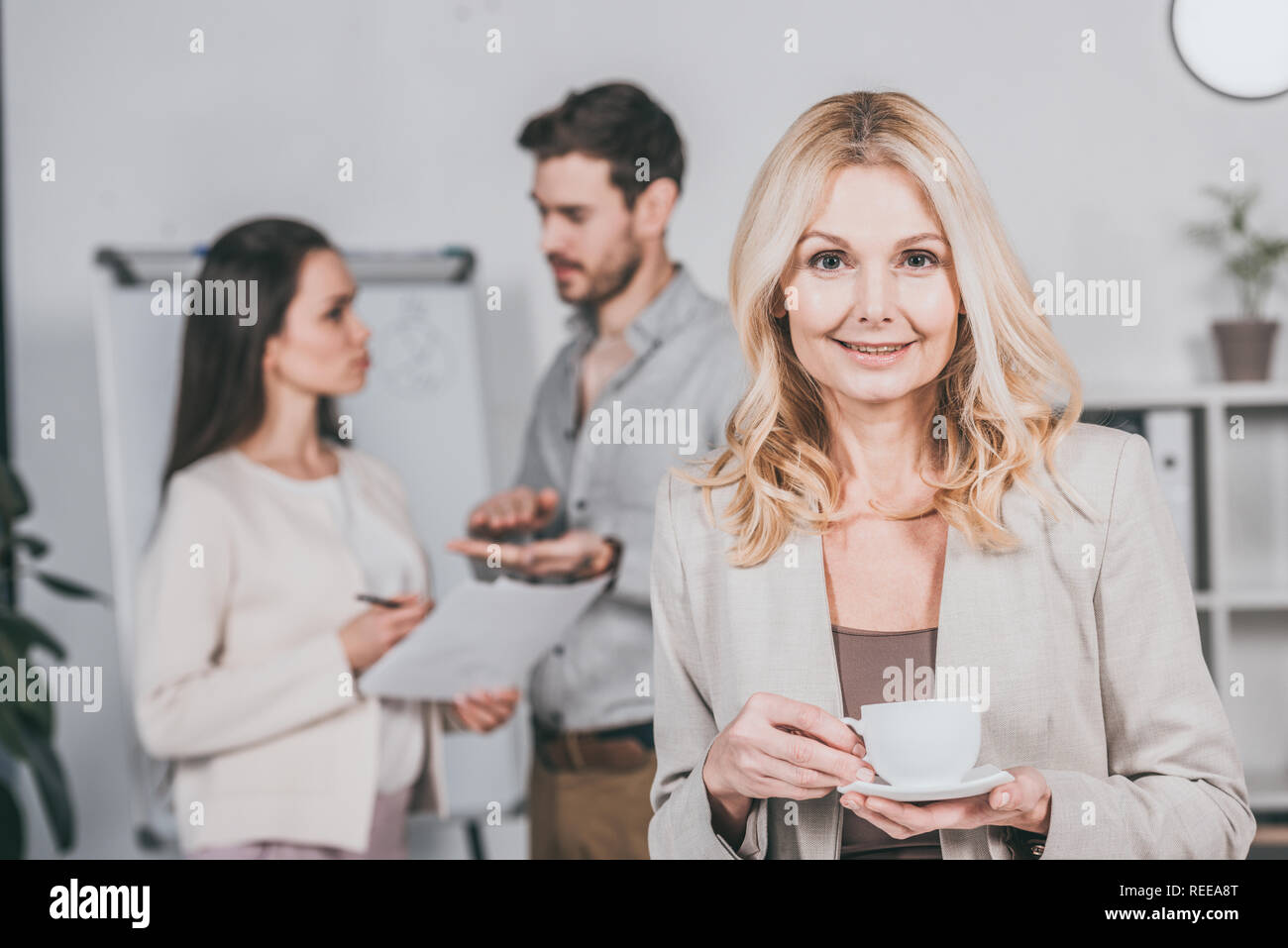 beautiful mature businesswoman holding cup of coffee and smiling at ...