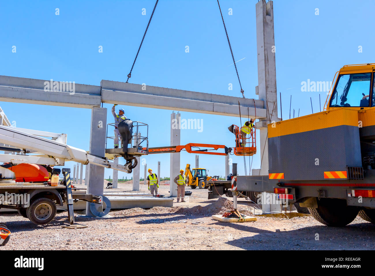 Worker is helping mobile crane to manage concrete joist for assembly ...