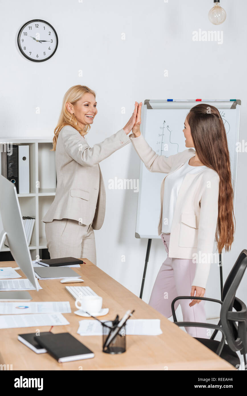 beautiful happy businesswomen smiling and giving high five in office ...