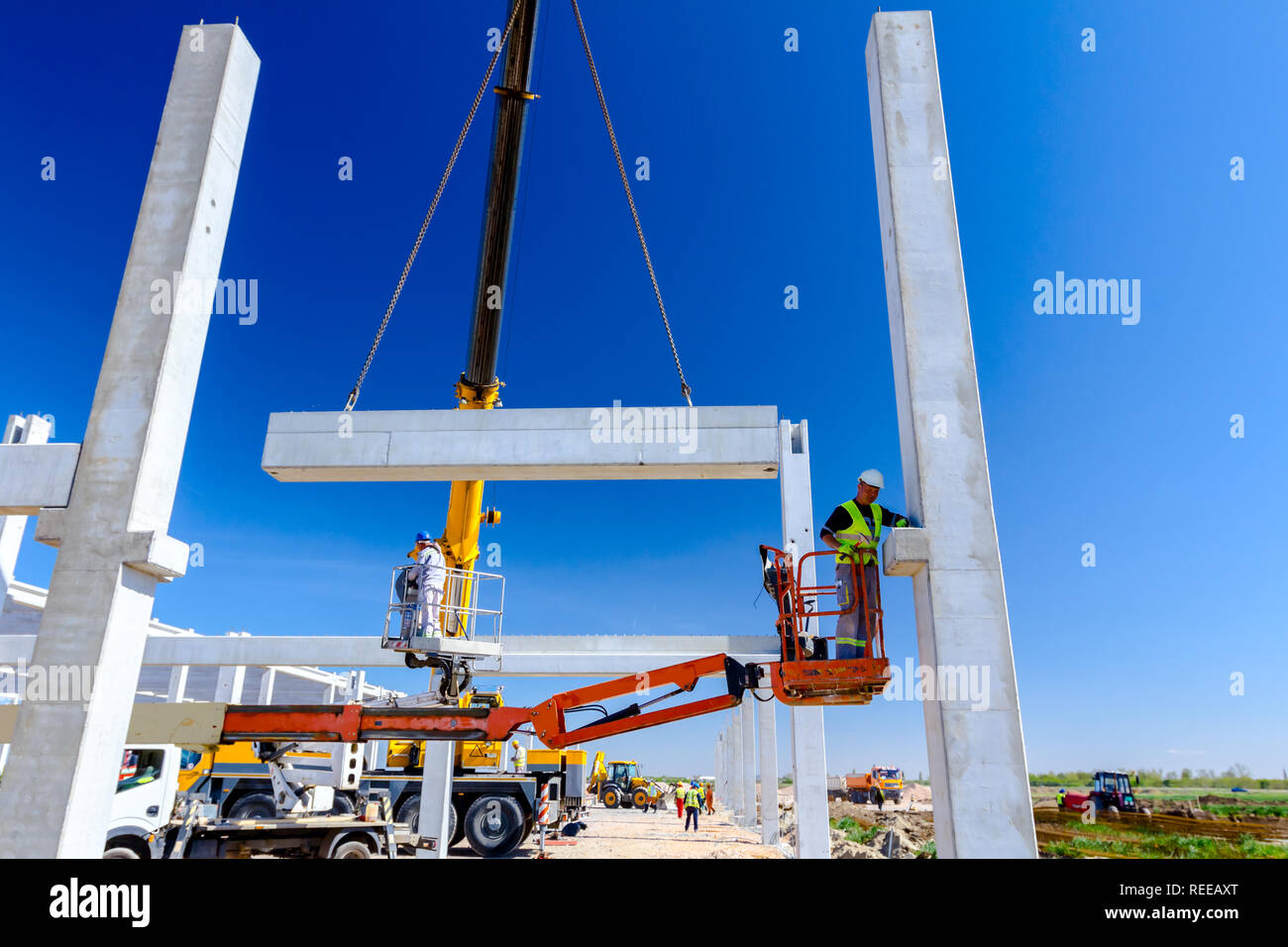 Worker is helping mobile crane to manage concrete joist for assembly ...
