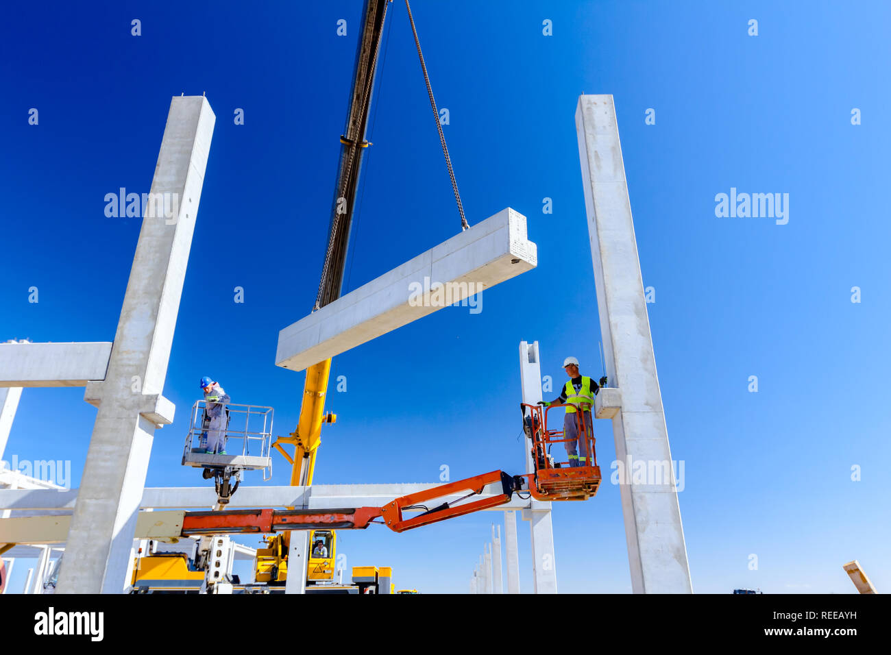 Worker is helping mobile crane to manage concrete joist for assembly ...