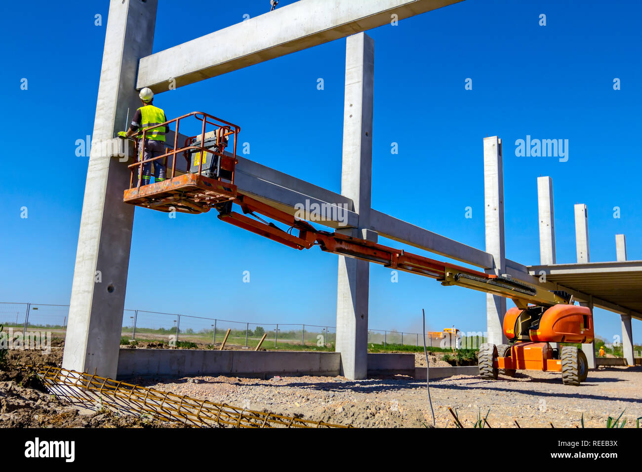 Worker is helping mobile crane to manage concrete joist for assembly ...