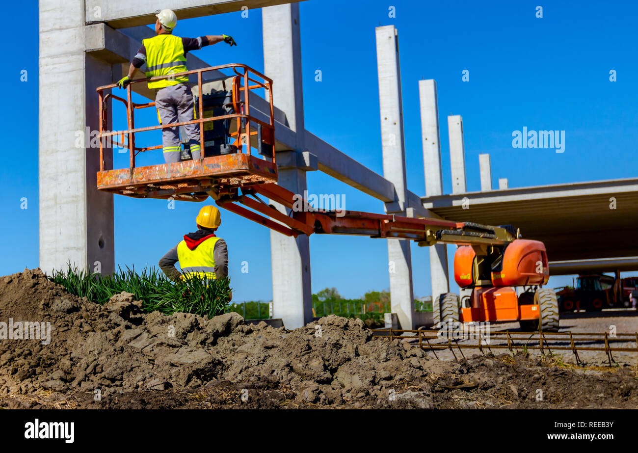 Worker is helping mobile crane to manage concrete joist for assembly ...