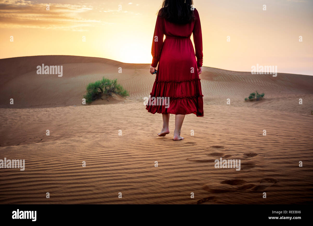 Woman walking in the desert at sunset Stock Photo