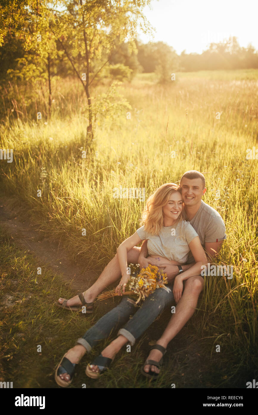 A young man embraces the belly of his pregnant wife while walking ...