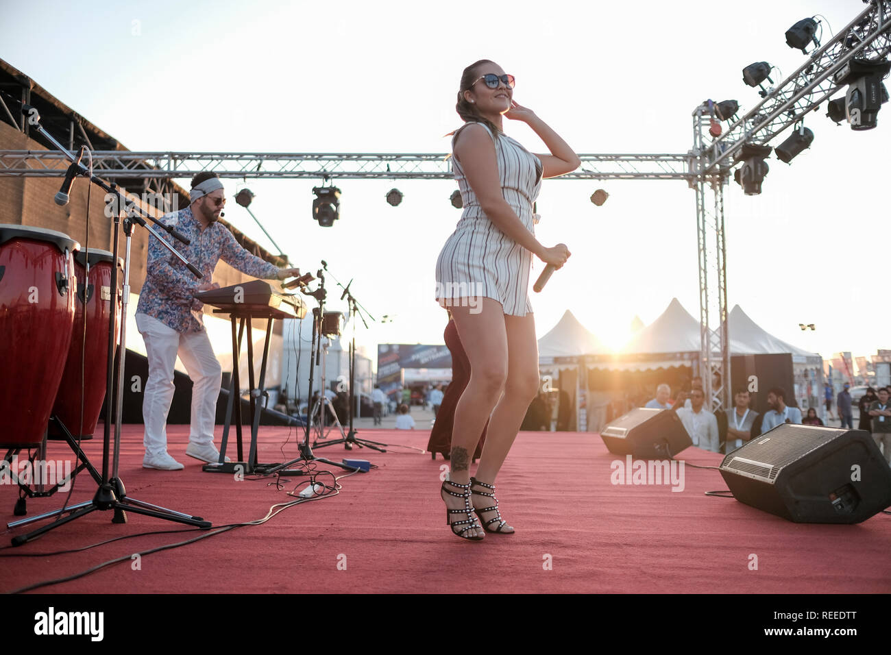 A young lady dancing and singing on stage against bright sun at F1H2O Abu Dhabi Stock Photo