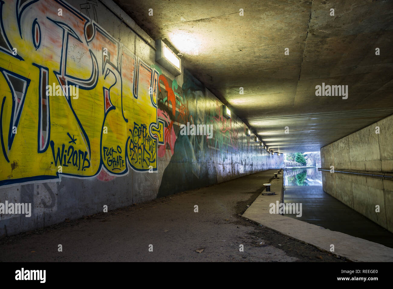 Landscape of canal side, subway graffiti sprayed on walls in pedestrian underpass, UK. Scourge of our waterways heritage or artistic expression? Stock Photo