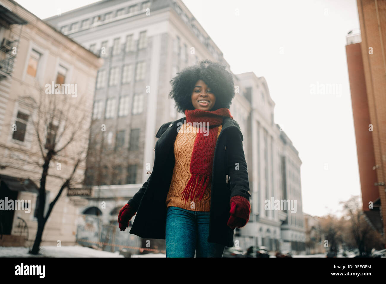 Happy young black woman is walking to the city street and smiling ...