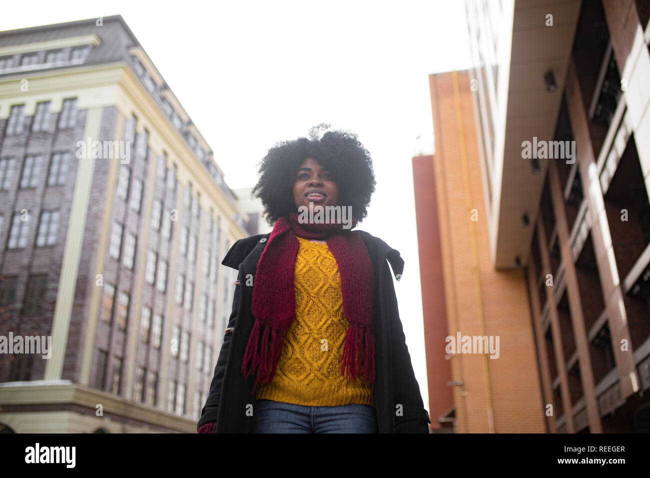 Happy young black woman is walking to the city street and smiling ...