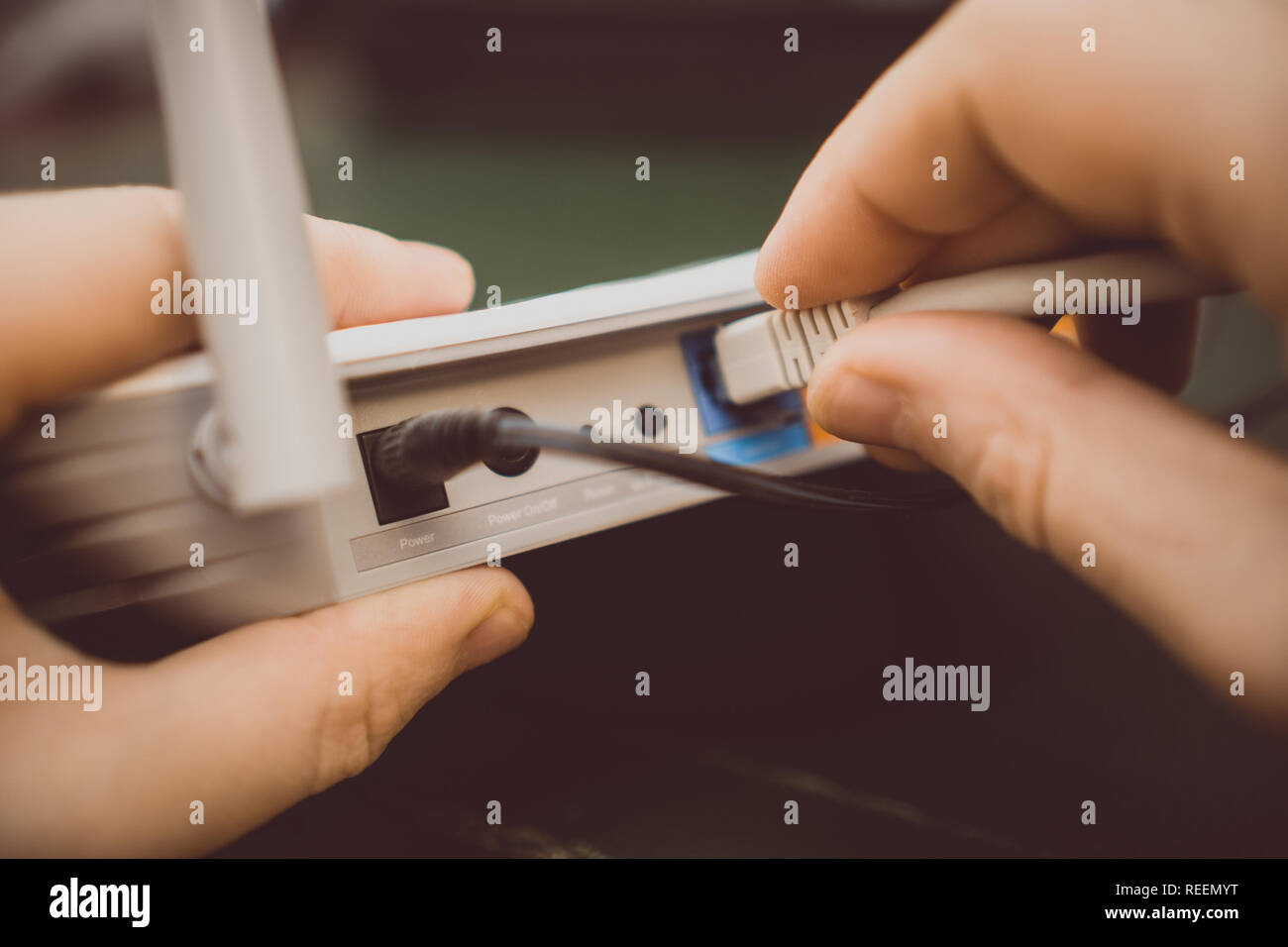 Man plugging internet cable into wifi router. Stock Photo