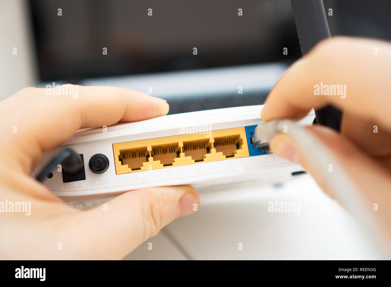 Man plugging internet cable into wifi router. Stock Photo