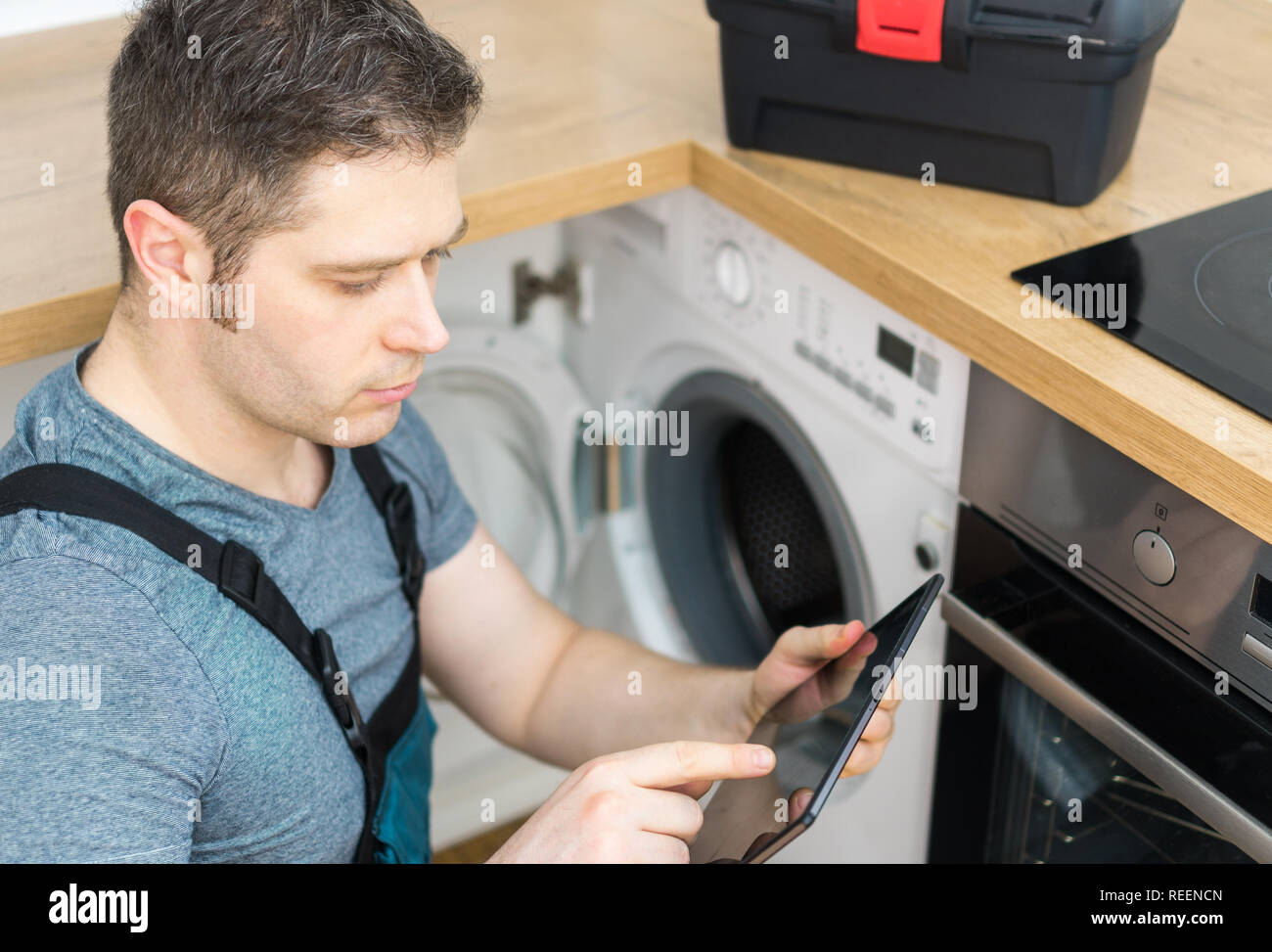 Handyman doing inspection of washing machine in the kitchen Stock Photo