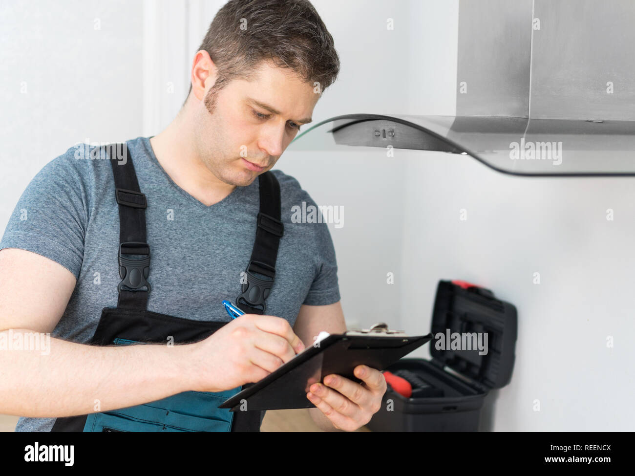Handyman doing inspection of exhaust hood in the kitchen Stock Photo