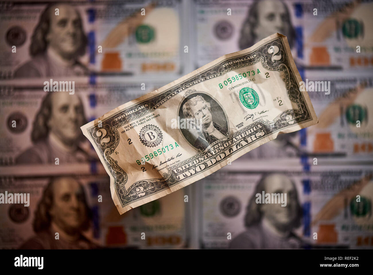 Two crumpled dollars on a blurred background of bills worth one hundred dollars the new American bill. Stock Photo