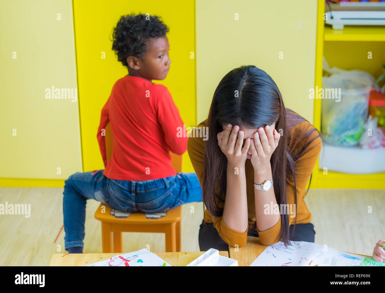 Teacher get headache with two naughty kids in classroom at kindergarten school Stock Photo