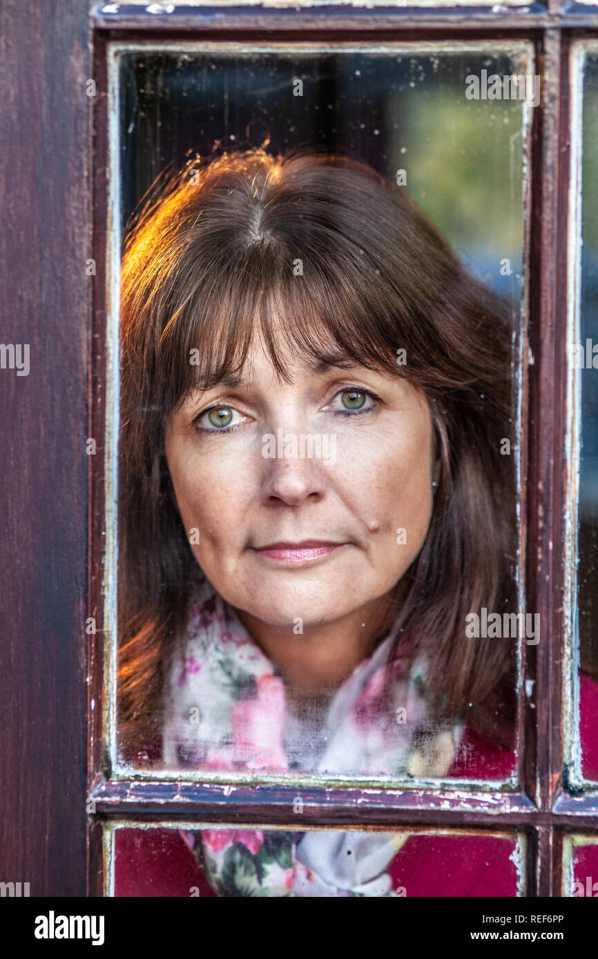 Model released attractive, single woman, looking out of a window Stock Photo