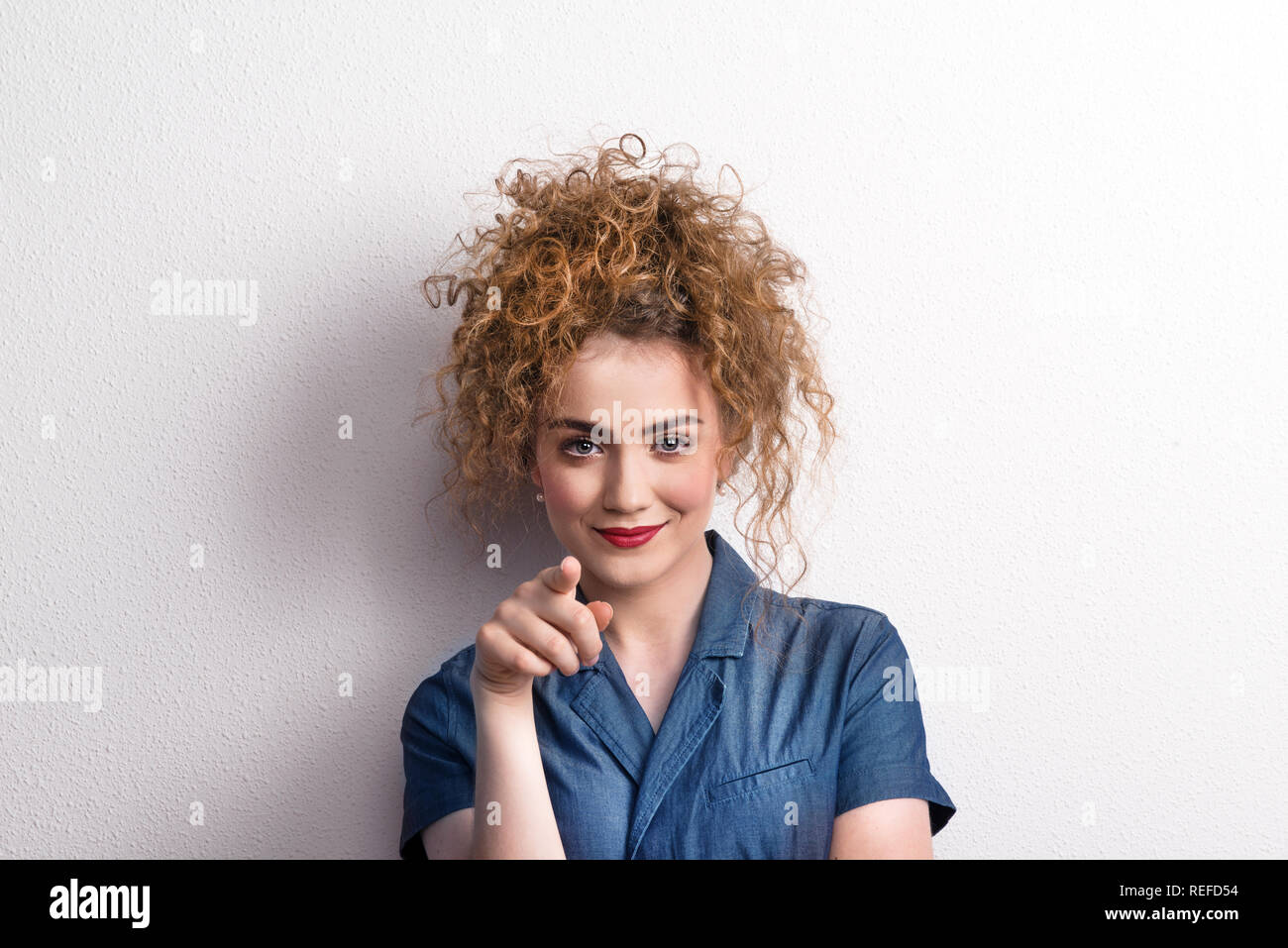 Young beautiful happy woman in studio, pointing at you. Stock Photo