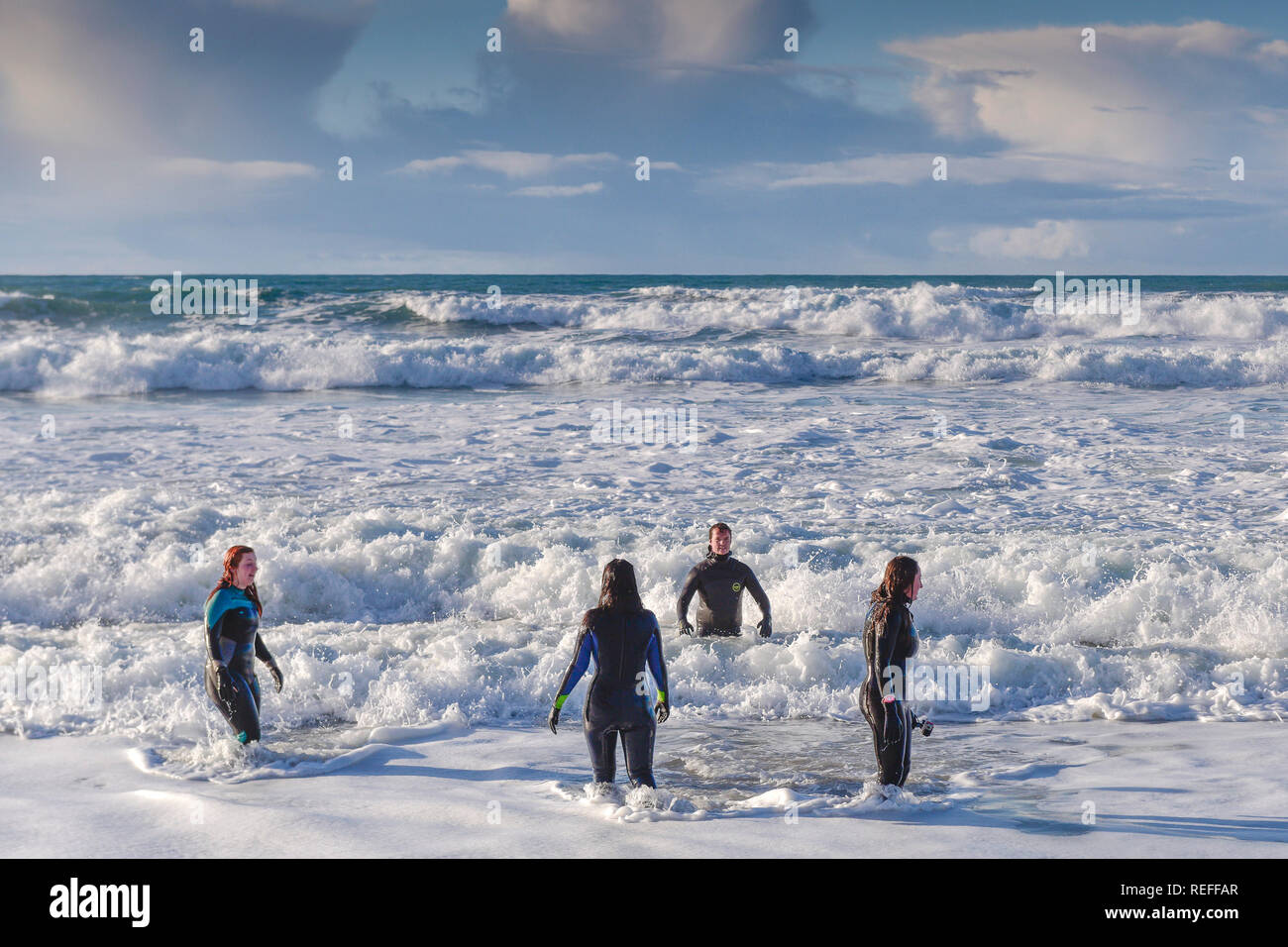 People in wetsuits standing in the sea at Fistral Beach in Newquay