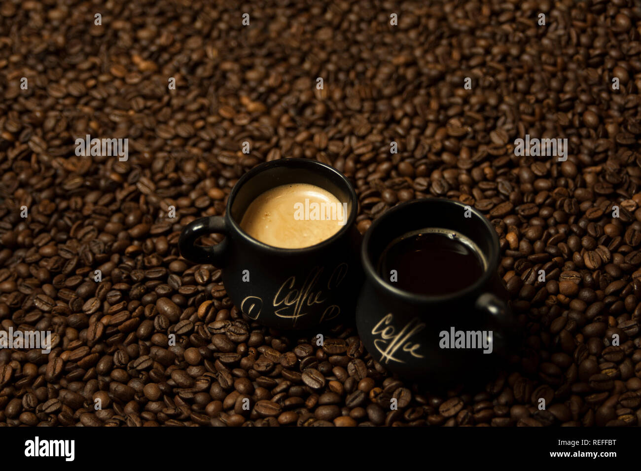 A cup of black coffee with milk standing on coffee beans. A healthy breakfast concept. Stock Photo