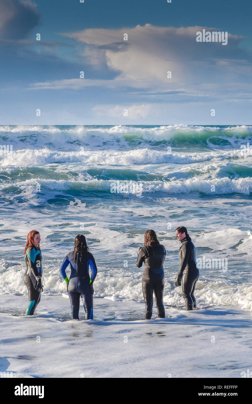 People in wetsuits standing in the sea at Fistral Beach in Newquay