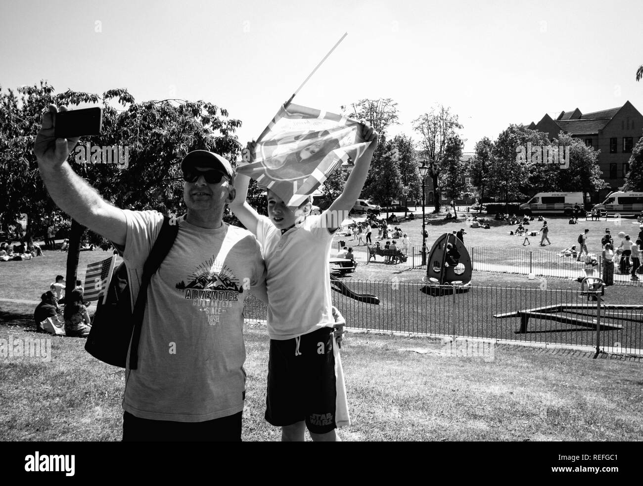 WINDSOR, UNITED KINGDOM - MAY 19, 2018: Father and son taking selfie with Prince Harry and Meghan Markel flag in Windsor after royal wedding - black and white  Stock Photo