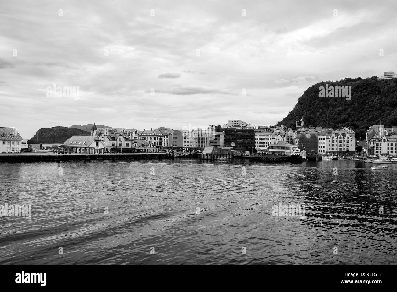 Alesund, Norway - January 16, 2010: town architecture and mountain from sea water on cloudy sky background. Vacation, traveling, wanderlust concept Stock Photo