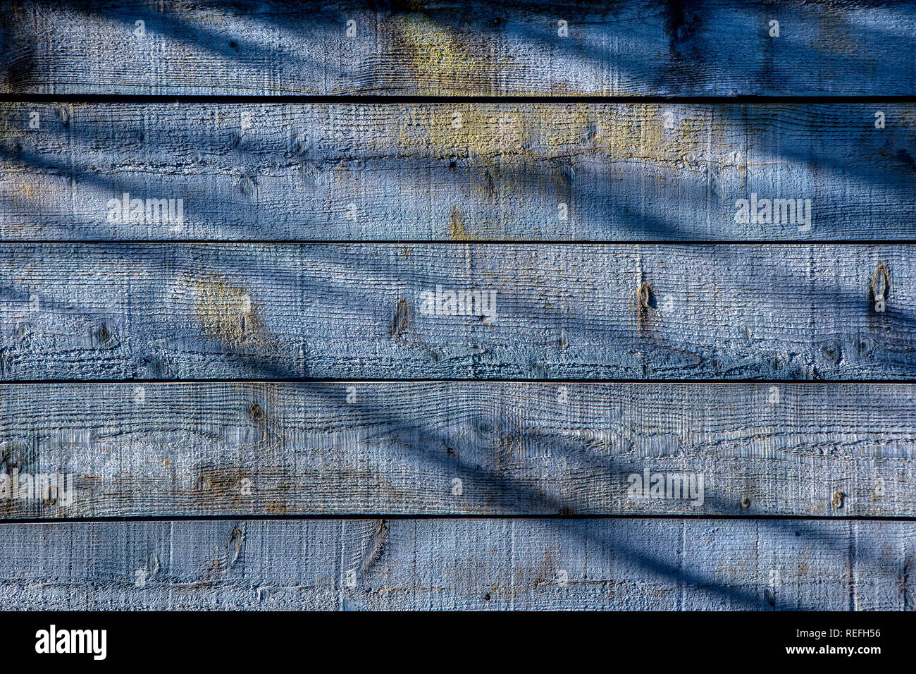 Blue wooden panels with shadows cast on them Stock Photo