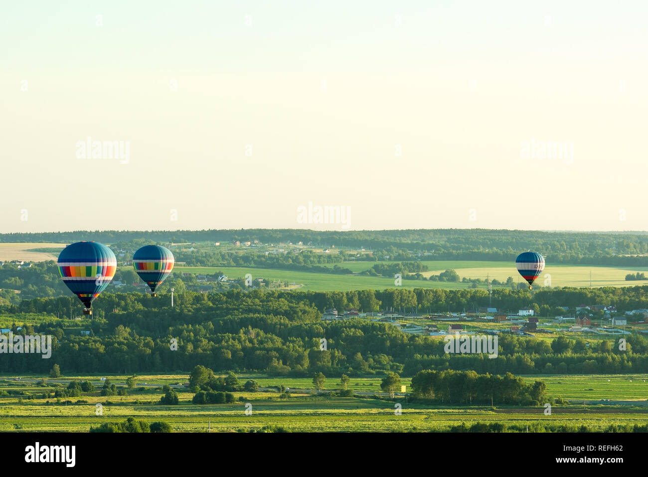 Flying in a balloon. Three objects in the air. Green fields and forests. Clear sky Stock Photo