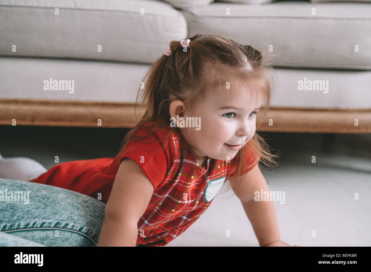 Close up little adorable thoughtful girl dreaming lying on a floor in a living room at modern home Stock Photo