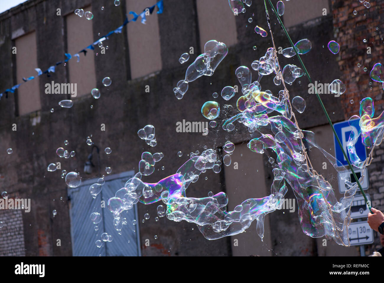 A freelance clown blowing hundreds of tiny, small and big bubbles at