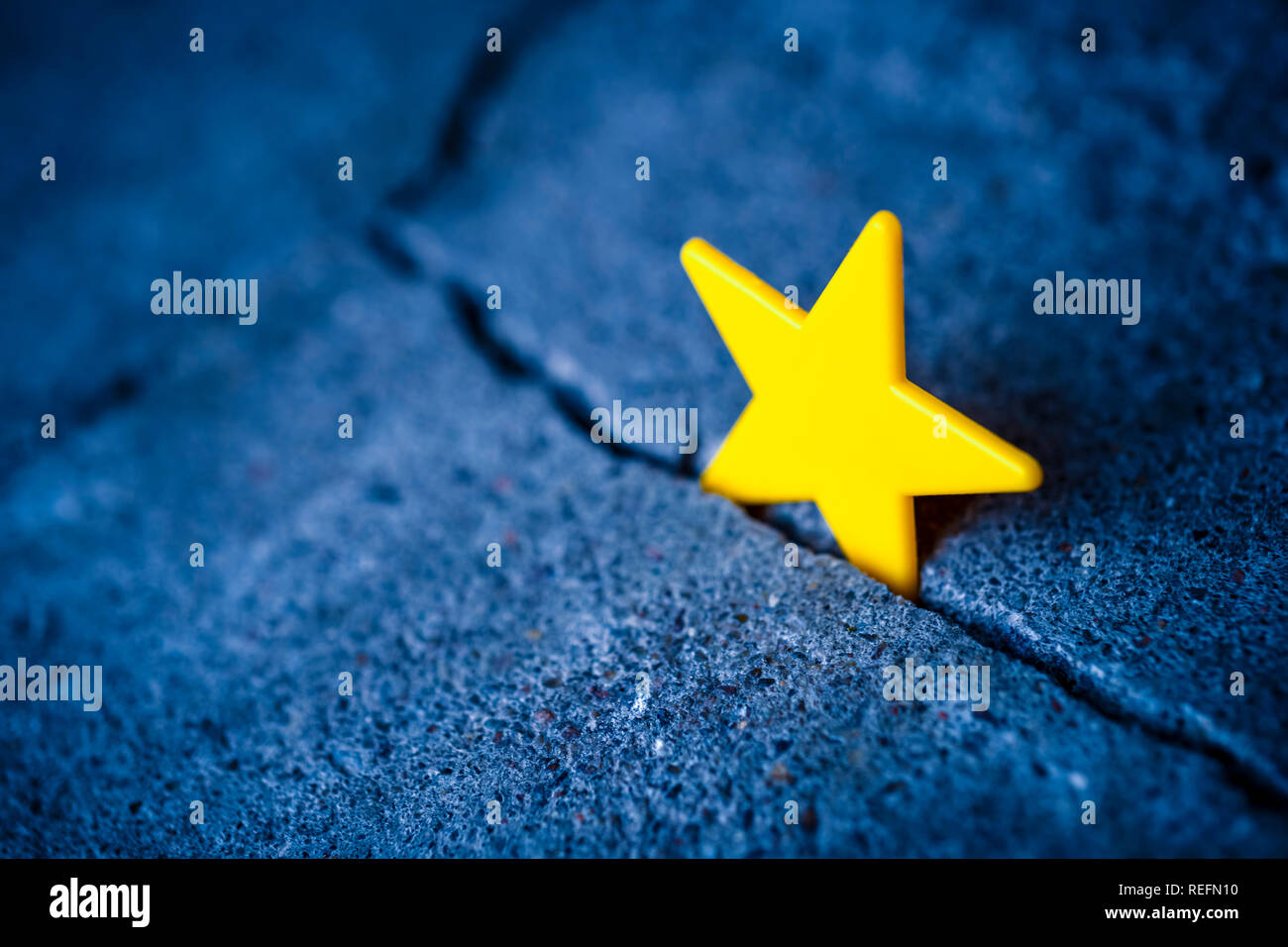 EU flag star in a gap in the ground, Brexit Stock Photo