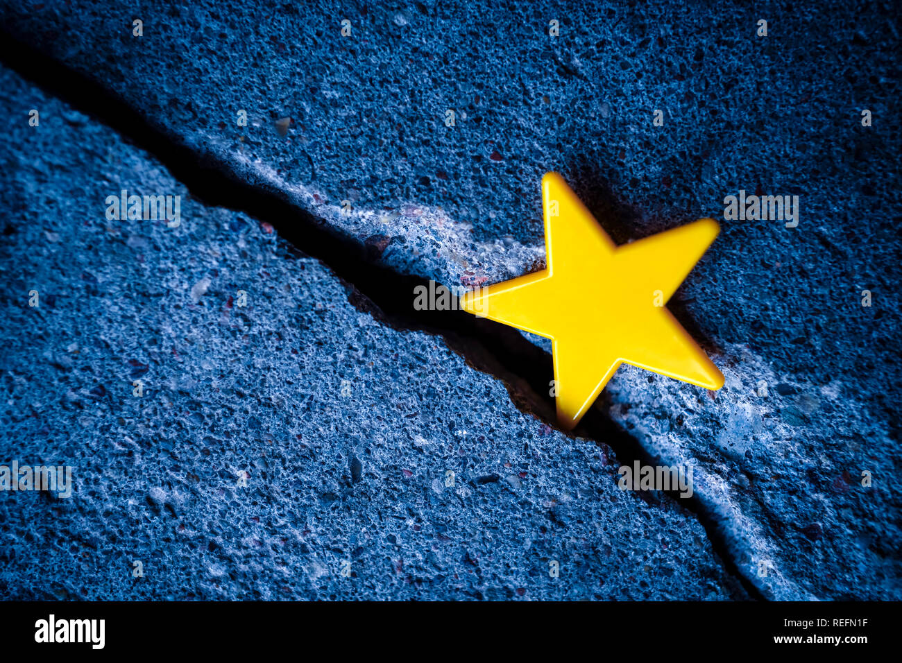 EU flag star in a gap in the ground, Brexit Stock Photo