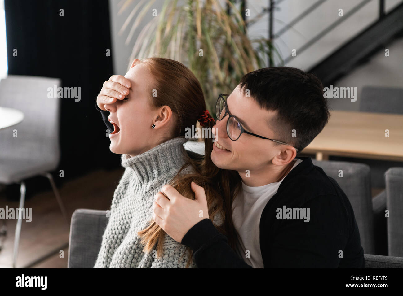 Surprise Beautiful romantic couple in cafe. Man is covering his girlfriend's eyes while she waiting for a surprise Stock Photo