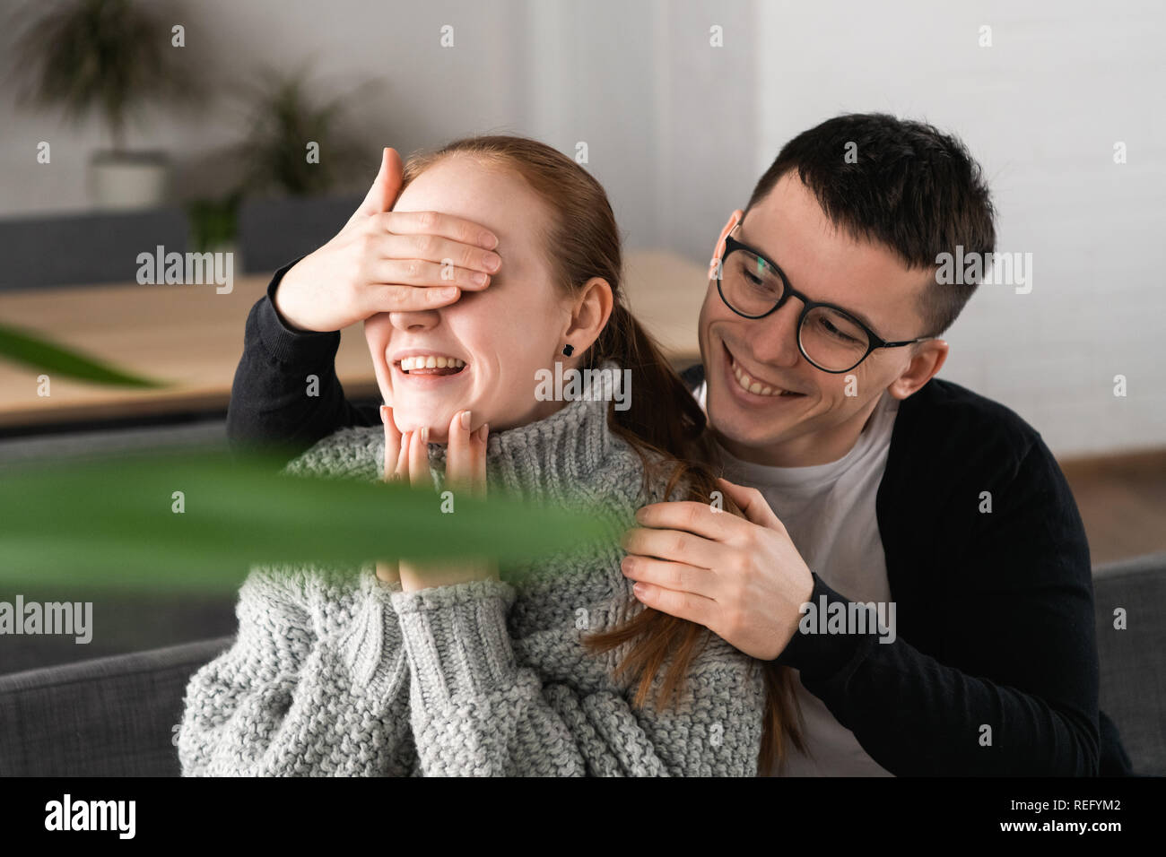 Surprise Beautiful romantic couple in cafe. Man is covering his girlfriend's eyes while she waiting for a surprise Stock Photo