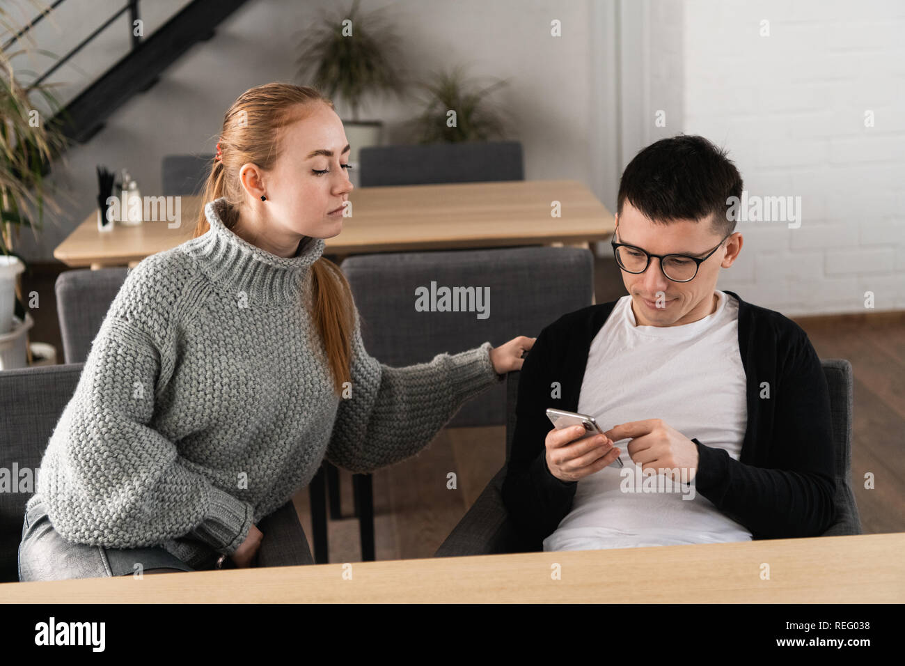 Girl suspects her man in cheating on her and spying sitting near in the cafe. Mistrust concept Stock Photo
